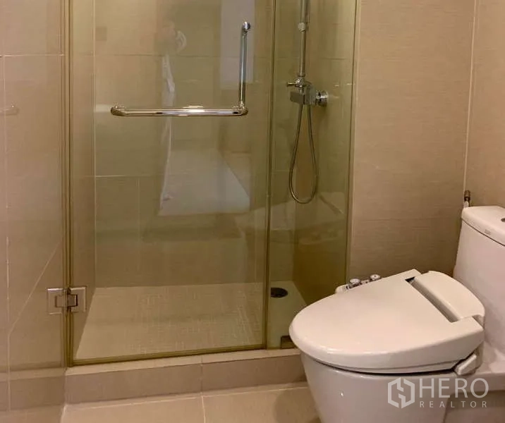 Condominium for rent - Close-up of glass shower and toilet with bidet seat.