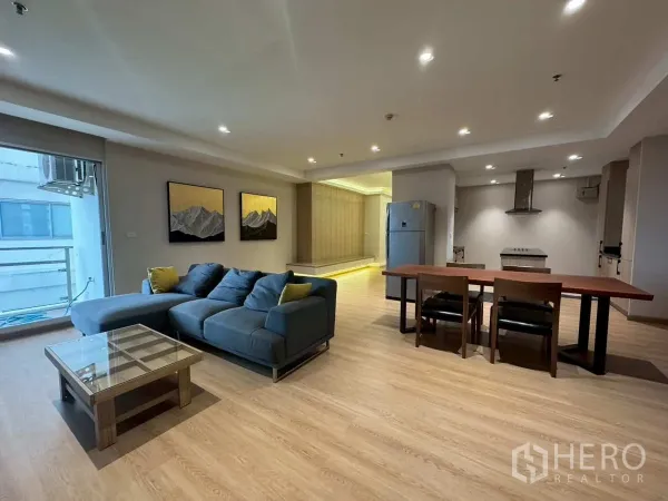 Condominium for rent or sale in Khlong Toei, Bangkok - Living area with sofa, dining table and open kitchen beside the balcony.