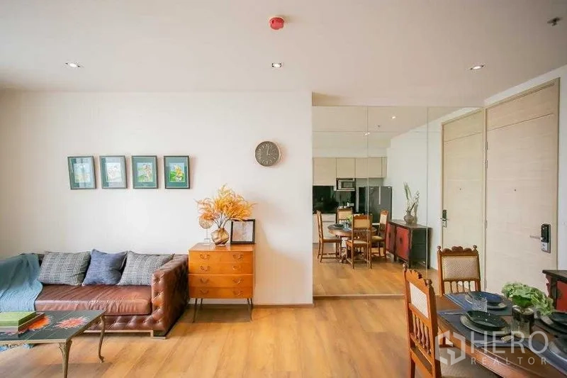 Condominium for sale in Khlong Toei, Bangkok - Spacious lounge and dining with a mirrored feature wall and ceiling downlights.