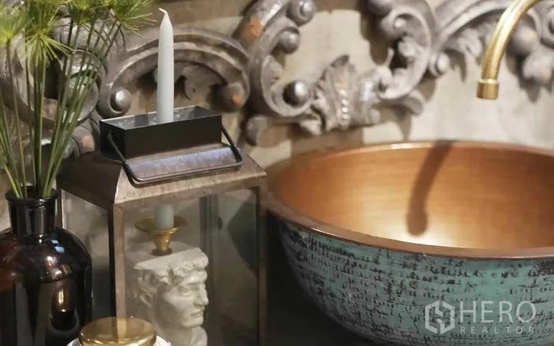Townhouse for rent in Watthana, Bangkok - Bathroom with carved mirror, concrete vanity and sculpted lion-head feature with planter.