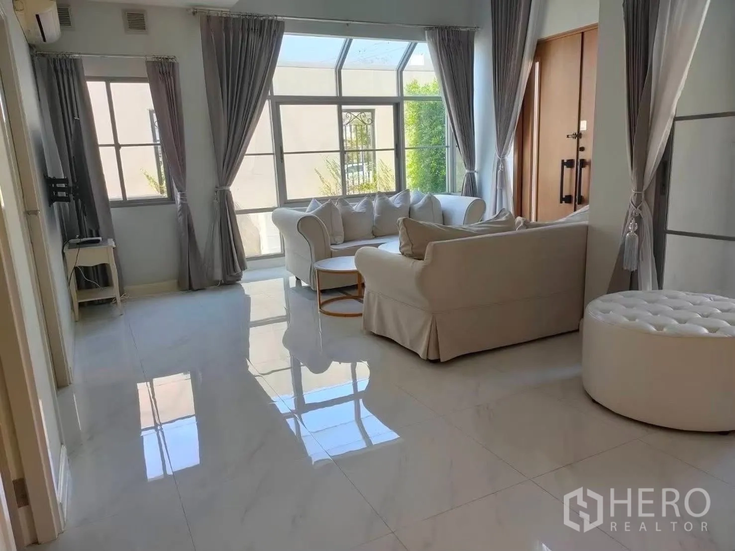บ้านเดี่ยว for rent in Bang Phli, Samut Prakan - ห้องรับแขกสว่างด้วยโซฟาสีขาว ชุดโต๊ะกลาง หน้าต่างบานใหญ่ และประตูไม้บานคู่