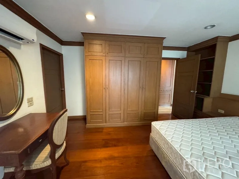 Condominium for rent in Watthana, Bangkok - Bedroom with full-height wardrobes, dressing table, and wood floors.