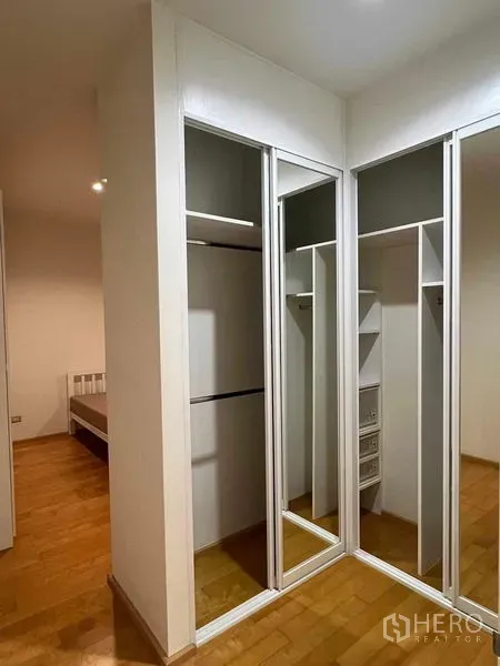 Condominium for rent in Ratchathewi, Bangkok - Walk-in closet with mirrored sliding doors and built-in storage beside the bedroom.