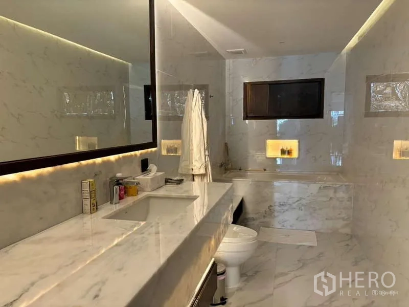 Condominium for rent in Watthana, Bangkok - Marble bathroom with soaking tub, large mirror and soft lighting.
