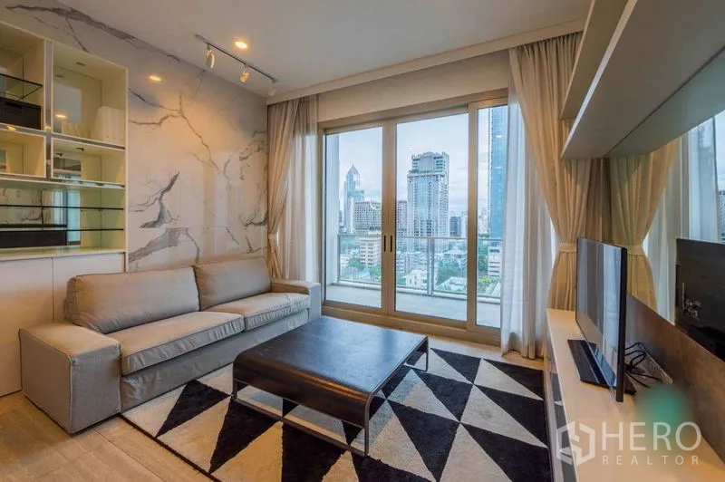 公寓 出租在Pathum Wan, Bangkok - 客厅配灰色沙发、电视柜与几何地毯，落地窗眺望曼谷天际线。