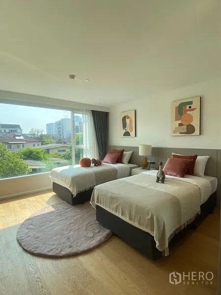 公寓 出租在Watthana, Bangkok - 采光充足的双床卧室，俯瞰绿意与低层建筑。
