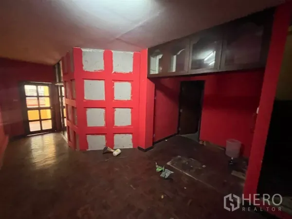Shophouse for rent in Watthana, Bangkok - Corridor with red walls, built-in upper cabinets and a glass-panel door.