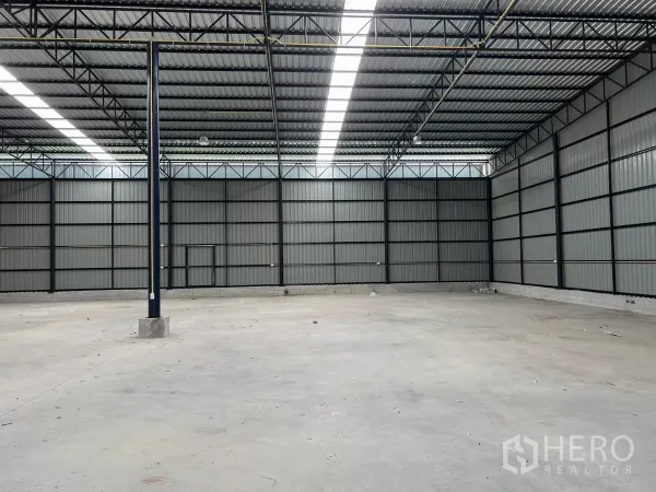 Warehouse for rent in Khlong Toei, Bangkok - Open industrial space featuring high ceilings, concrete flooring, and black steel columns.