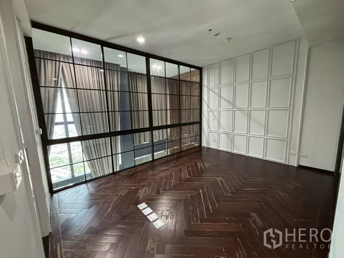 Condominium for sale in Bang Kho Laem, Bangkok - Mezzanine bedroom behind black-framed glass wall overlooking the double-height living space.
