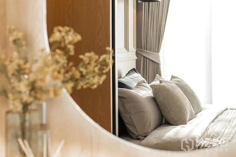 Condominium for rent in Khlong Toei, Bangkok - Mirror view highlighting dried flowers and a neatly made bed with layered pillows.