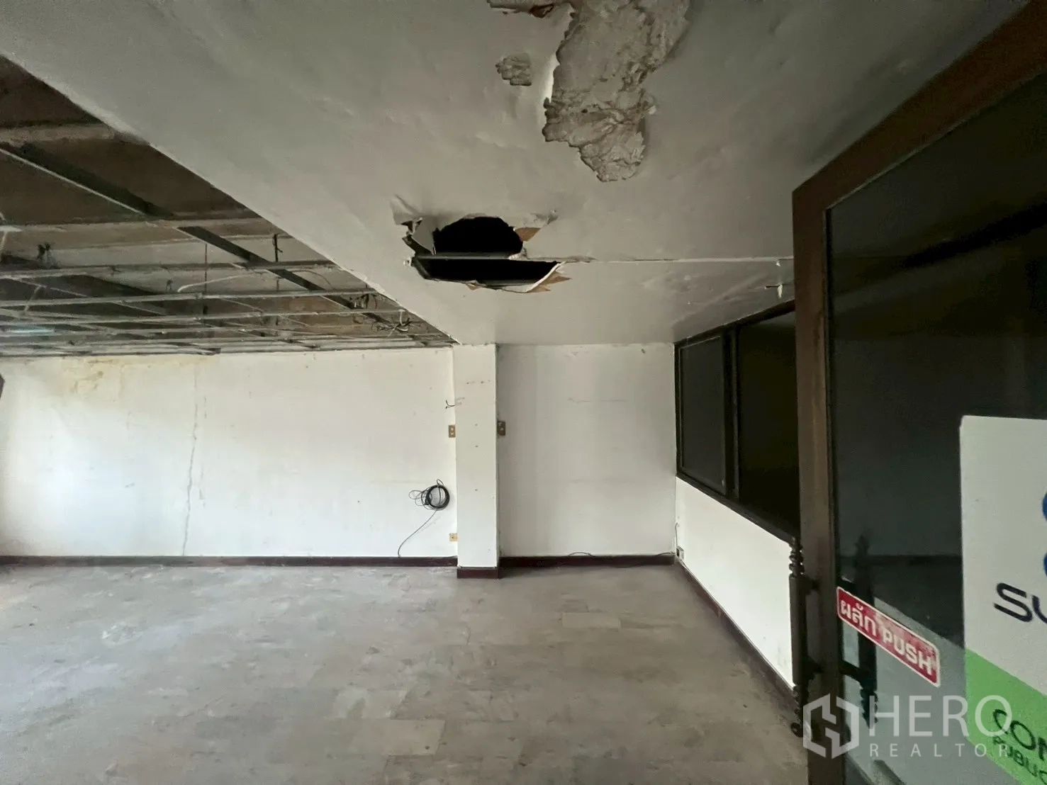 Shophouse for rent in Phra Khanong, Bangkok - Close-up of unfinished ceiling and open room with glass door frontage.