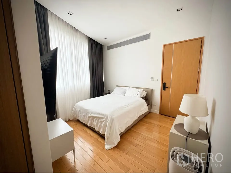 Condominium for rent or sale in Khlong Toei, Bangkok - Bedroom with double bed, large window with curtains, bedside lamp, and wall-mounted TV.