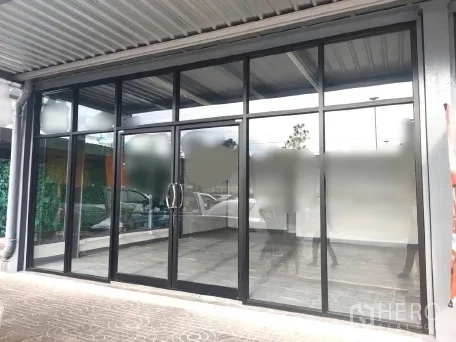 Retail Space for rent in Khlong Toei, Bangkok - Full-width glazed shopfront under a canopy with entry doors and parking in front.