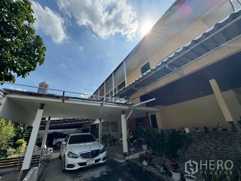 独立式住宅 出租在Watthana, Bangkok - 两层住宅外立面，带有有顶车棚与多盆绿植。