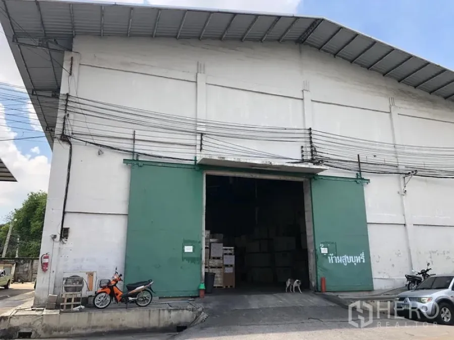 คลังสินค้า ให้เช่าในRat Burana, Bangkok - ภายนอกโกดังอุตสาหกรรม เพดานสูง ประตูเหล็กสีเขียวขนาดใหญ่ ทางเข้าขนส่งกว้าง และลานคอนกรีต ในเขตราษฎร์บูรณะ กรุงเทพฯ