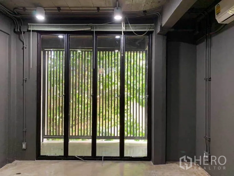 Home Office for rent in Huai Khwang, Bangkok - Interior view of tall black-framed windows with vertical slats and greenery.