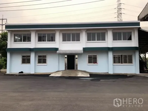 Factory for rent in Lam Luk Ka, Pathum Thani - Front view of a freshly painted two‑storey office building with barred windows.