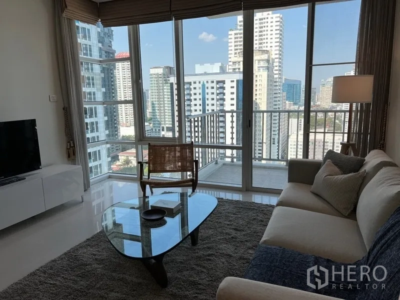 公寓 出租在Watthana, Bangkok - 转角客厅面向整面玻璃与城市景观，并通往小阳台。