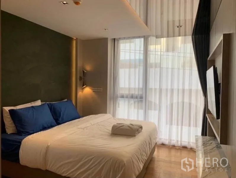 公寓 出租在Watthana, Bangkok - 主卧配大床、电视与落地窗和纱帘。