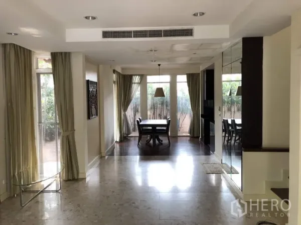 Detached House for sale in Wang Thonglang, Bangkok - Spacious living and dining zone with floor-to-ceiling windows, recessed lighting, and a mirrored wall.
