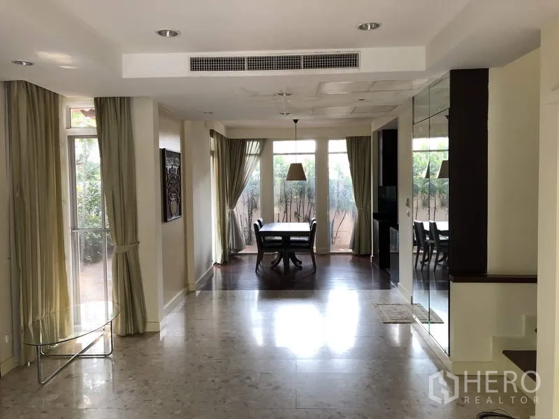 Detached House for sale in Wang Thonglang, Bangkok - Spacious living and dining zone with floor-to-ceiling windows, recessed lighting, and a mirrored wall.
