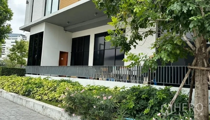 零售空间 出租 - 现代商铺外立面，落地黑框玻璃与遮蔽露台，前方绿化带