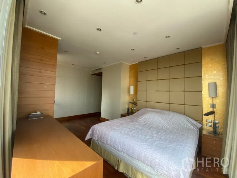 Condominium for rent in Sathon, Bangkok - Master bedroom with padded headboard, warm wood accents and recessed ceiling lights.