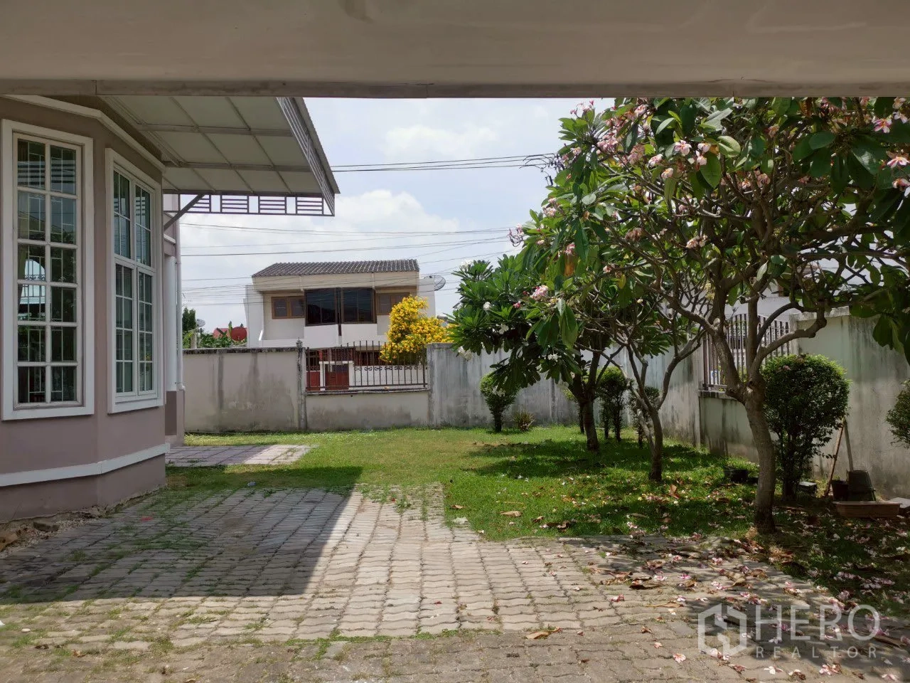 独立式住宅 出售在Phra Khanong, Bangkok - 从车棚看前院，飘窗、车道与开花树。
