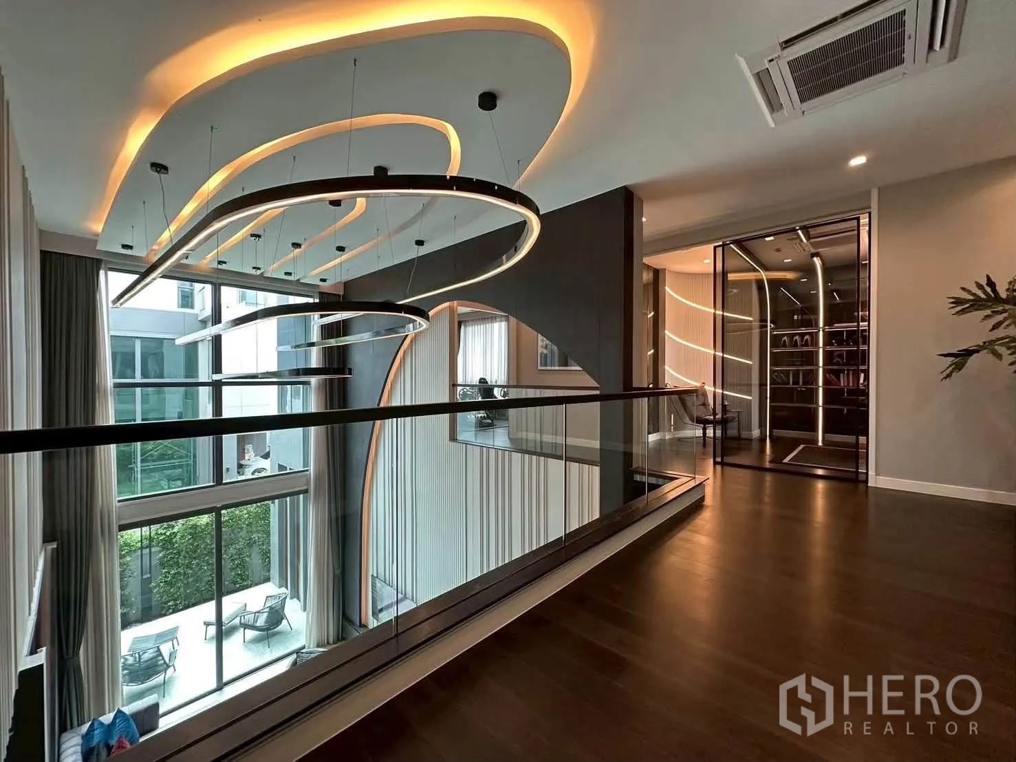 独栋房屋 for rent or sale in Suan Luang, Bangkok - 楼层走廊设弧形吊灯，俯瞰挑高中庭与玻璃护栏。