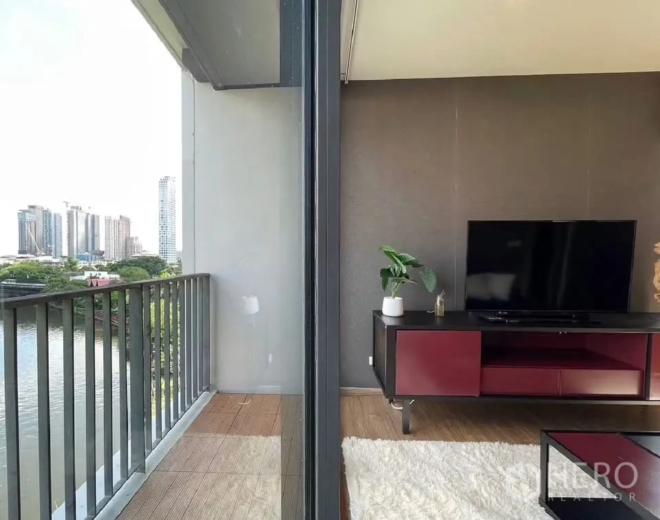 Condominium for rent in Watthana, Bangkok - Balcony with railing overlooking the river next to the living room and TV console.