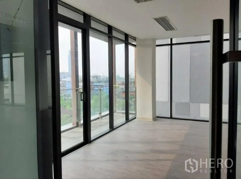 Office Space for rent in Bang Kho Laem, Bangkok - Corner office area with sliding glass doors and balcony railing overlooking the neighborhood.