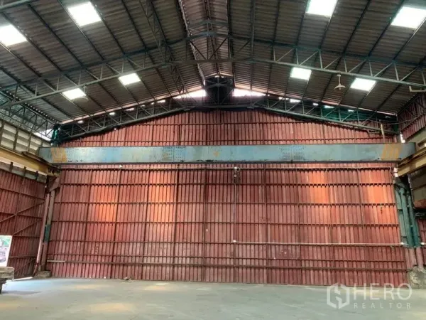 Warehouse for rent in Bang Kho Laem, Bangkok - End wall beneath a peaked steel roof with skylight panels inside the warehouse.