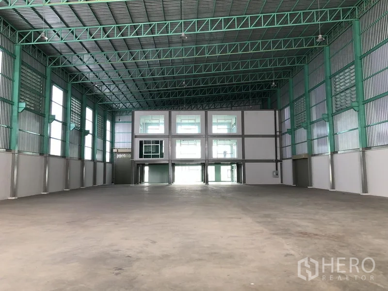 Factory for rent or sale in Bang Phli, Samut Prakan - Warehouse interior facing mezzanine offices beneath a tall ceiling.