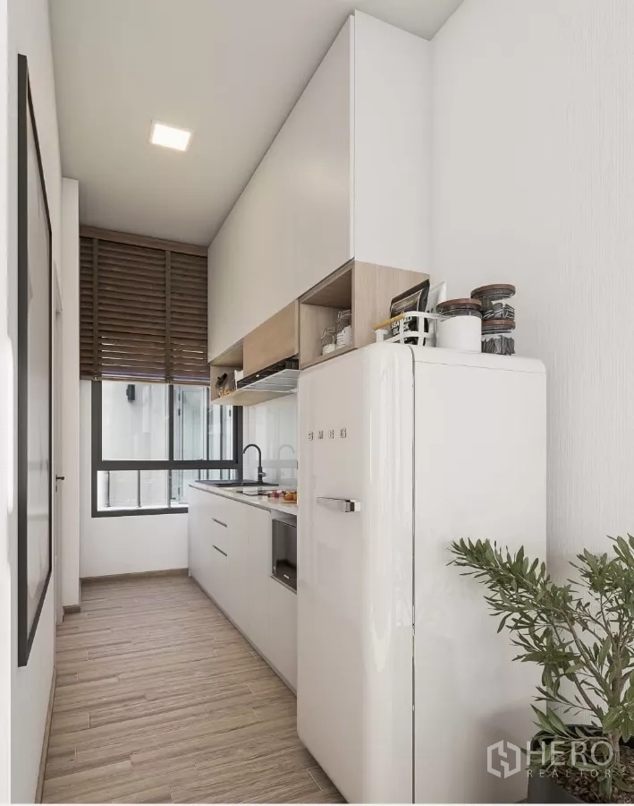 Townhouse for rent in Chatuchak, Bangkok - Compact kitchen with white cabinetry, window and retro‑style refrigerator.