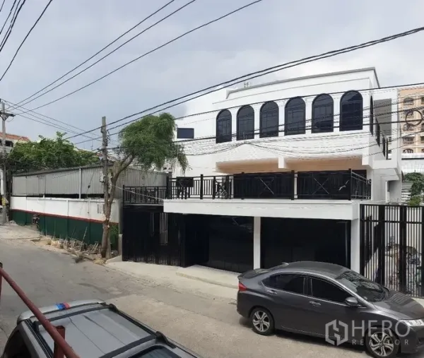 Home Office for rent or sale in Bang Na, Bangkok - Street view of the home office showing a large terrace and secure black fencing.