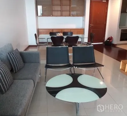 Condominium for rent in Pathum Wan, Bangkok - Bright living room with gray sofa, glass coffee table, and dining set on tiled flooring.