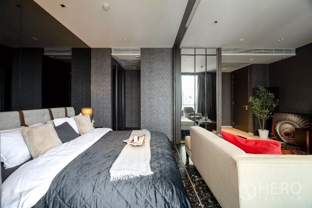 Condominium for rent or sale in Khlong Toei, Bangkok - King bed with sofa, dark marble flooring and mirrored closet doors.