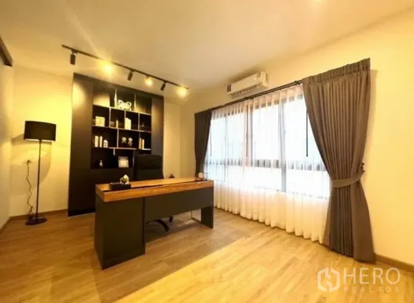Townhouse for rent - Home office with desk, shelving, track lighting, and wide curtained window.