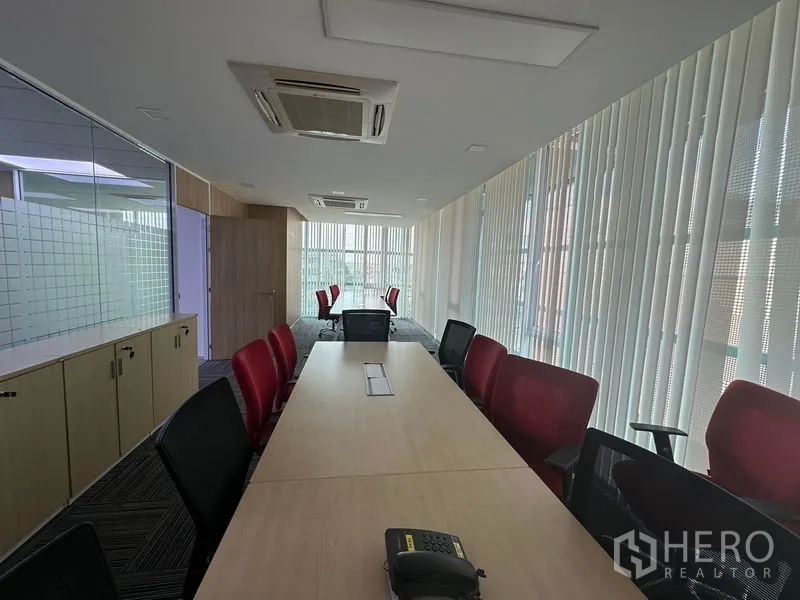 Office Space for rent - Boardroom with long meeting table, TV screen, glass partition and vertical blinds.