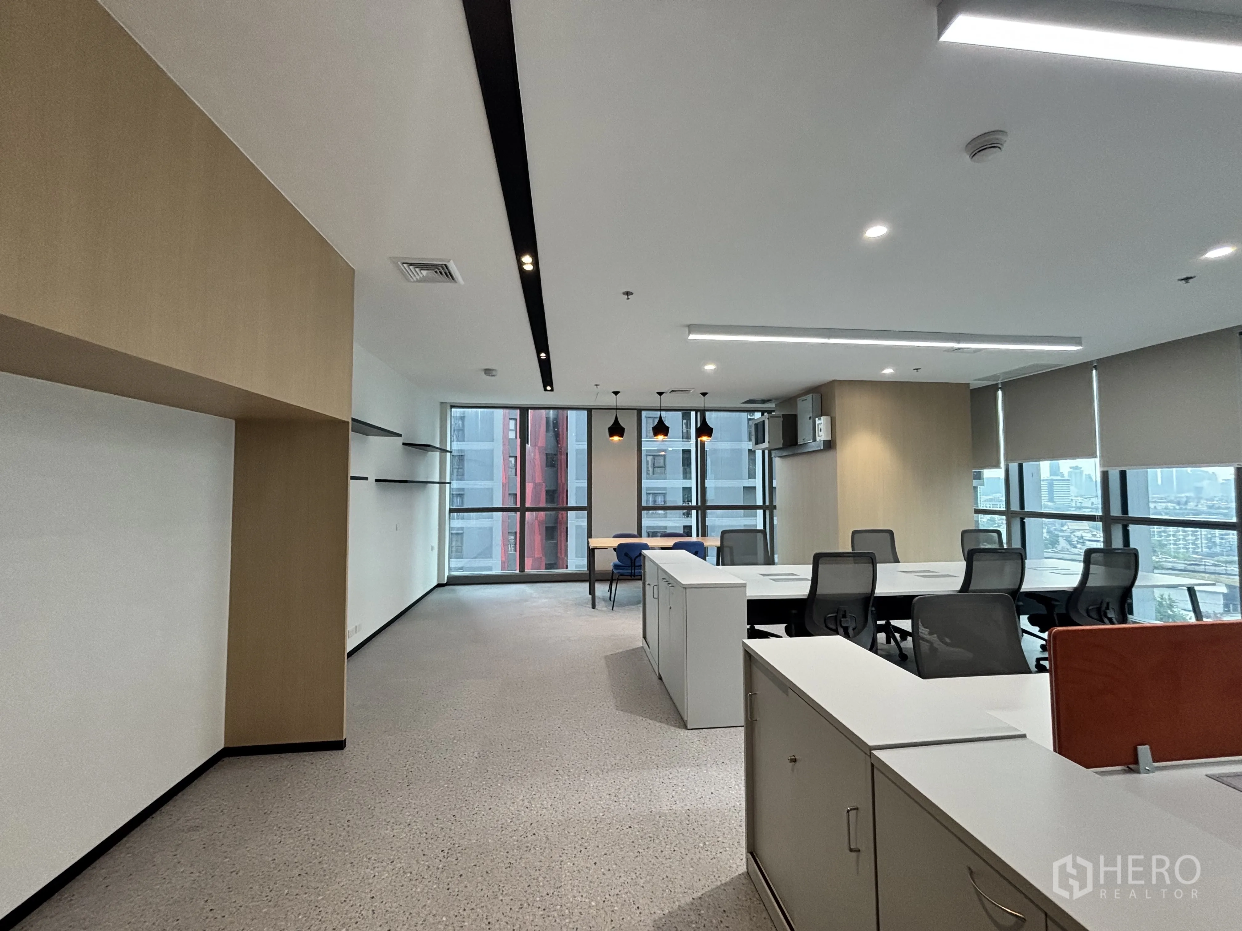 Office Space for rent in Huai Khwang, Bangkok - Spacious office area with pendant lights, wall shelving and large windows overlooking nearby towers.