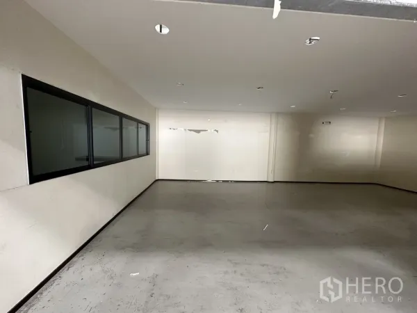 Warehouse for rent in Suan Luang, Bangkok - Ground-floor office room with a long internal observation window facing the warehouse.