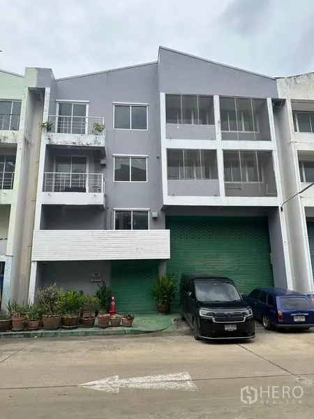 Factory for rent or sale in Khlong Luang, Pathum Thani - Three-storey factory facade with green roller shutter and parking in Khlong Luang.