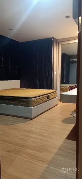 Detached House for rent or sale in Khan Na Yao, Bangkok - Cozy bedroom with wood floors, bed base and mirrored wardrobe with dark drapes.