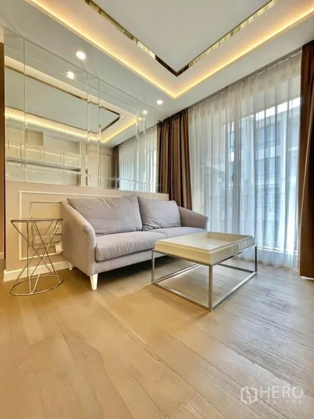公寓 出售在Huai Khwang, Bangkok - 明亮客厅，沙发与茶几，镜面墙和落地窗帘的曼谷公寓。