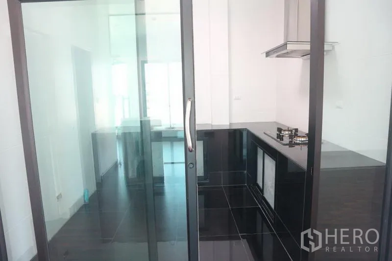 Factory for sale in Bang Pakong, Chachoengsao - Compact pantry with black cabinetry seen through a sliding glass door.