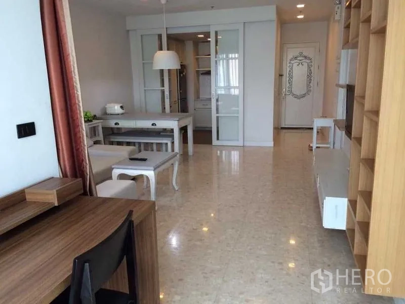 Condominium for rent in Khlong Luang, Pathum Thani - Open-plan dining and entry area with glossy tile floors, built-in shelving and glass doors to the kitchen.