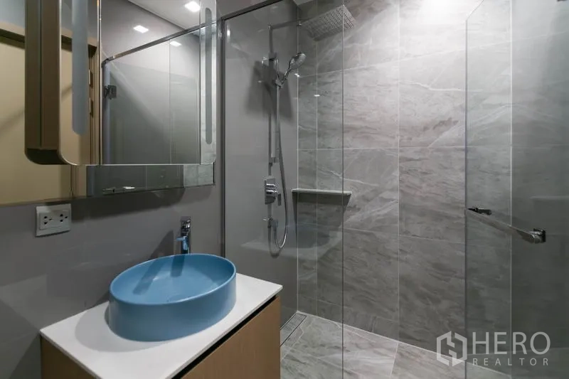 Condominium for rent in Watthana, Bangkok - Modern bathroom with glass shower, rain head and blue vessel sink on vanity.