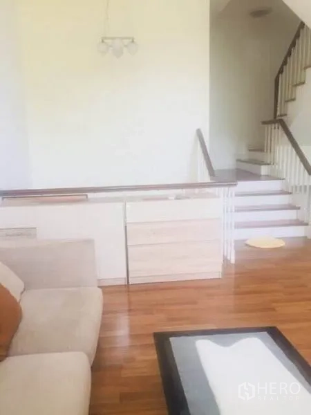 Townhouse for rent in Bang Kapi, Bangkok - Open living space with wooden floors and staircase with white balustrade.