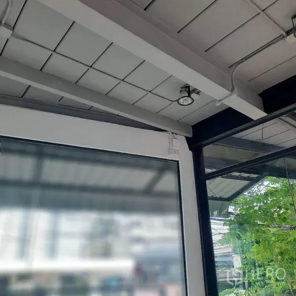 零售空间 出租在Lat Phrao, Bangkok - 外露天花与轨道射灯，旁有玻璃隔墙与金属梁。