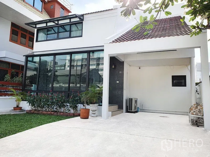 独立式住宅 出租在Phra Khanong, Bangkok - 两层独栋外观，大面积玻璃日光房与车棚，庭院草坪。